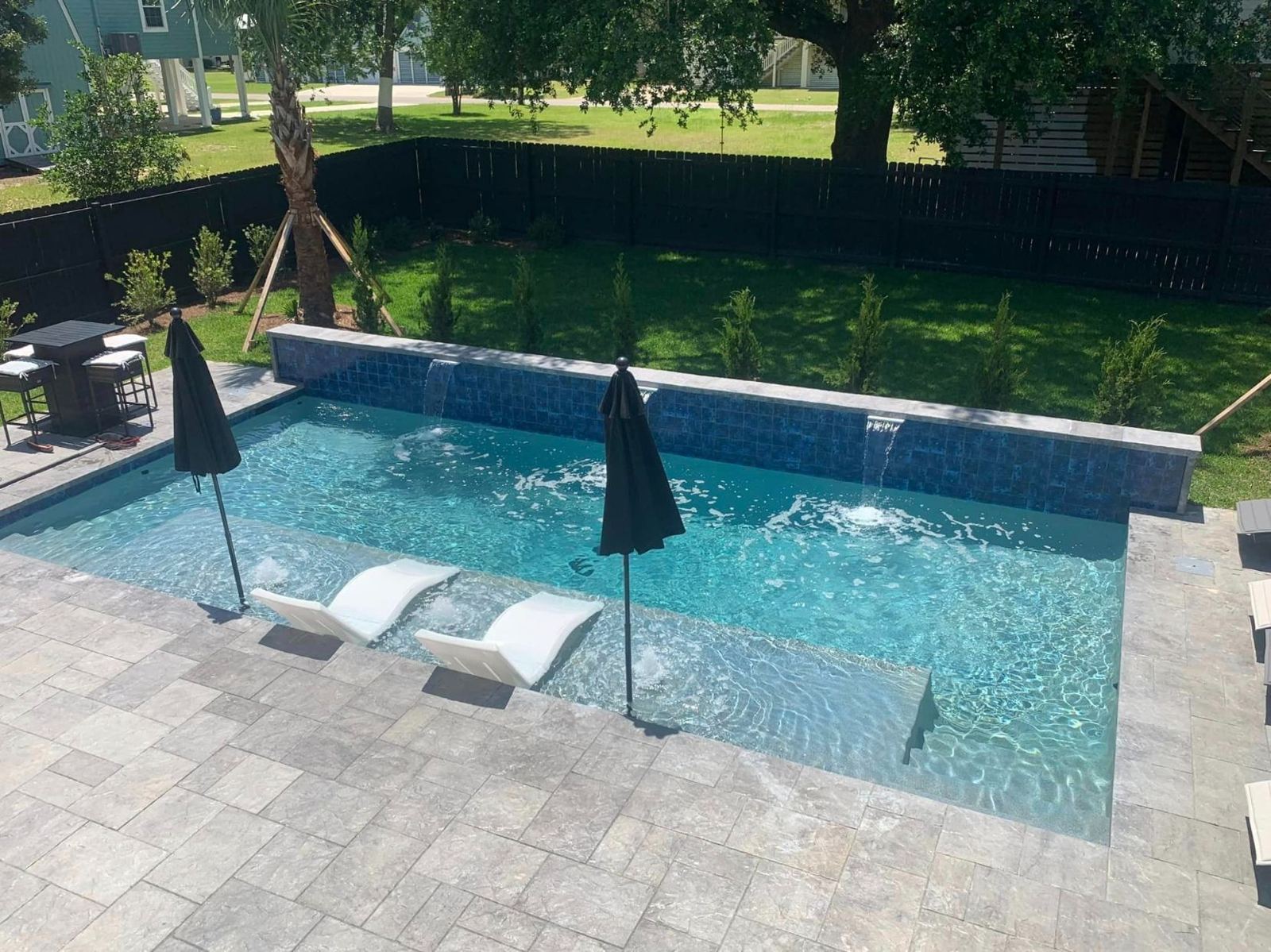 Pool with tanning ledge, umbrellas and paver deck